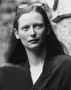 black and white photograph of a woman with glasses on her head looking at the camera