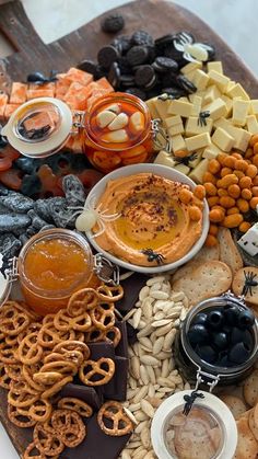 an assortment of snacks and dips on a platter with crackers, pretzels, nuts, cheese