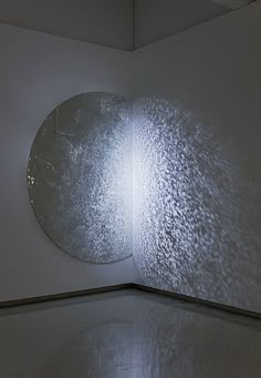 a white room with a large circular mirror on the wall and light shining through it