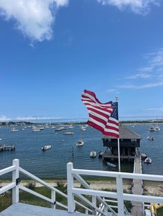 an american flag flying on the side of a boat dock with boats in the water