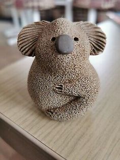 a ceramic koala sitting on top of a wooden table