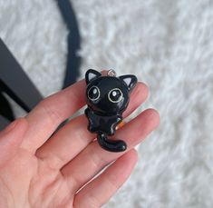 a hand holding a small black cat charm