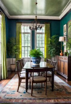 a dining room with blue walls and green drapes on the windowsills is shown