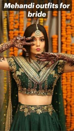 a woman in a green and gold lehenga with her hands on her head