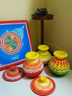 there are many colorful vases sitting on the table next to each other and a framed painting