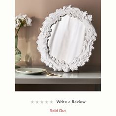 a white mirror sitting on top of a table next to a vase with flowers in it