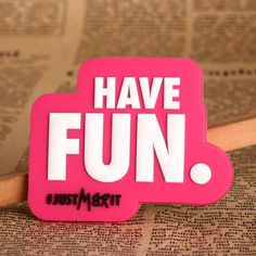 a pink sticker with the words have fun on it sitting next to a newspaper