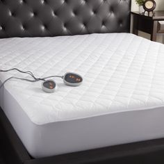 an alarm clock sitting on top of a white mattress