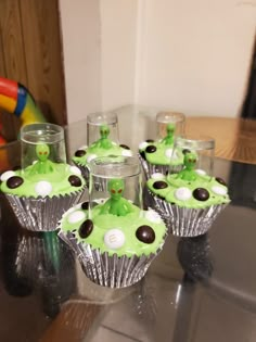 some cupcakes with green icing and chocolate on them sitting on a table