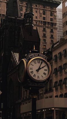 a clock on a pole in front of some buildings and other tall buildings with windows