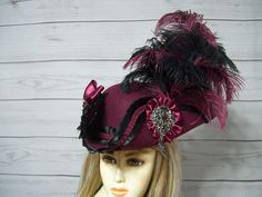 Beautiful burgundy woolen pirate hat with black and burgundy ostrich feathers, burgundy bows, burgundy cocarde with a large sparkly jewel center, black satin pleated trim with burgundy braided trim. This hat is about 22 1/2" for the inside circumference with a built-in hat sizer for a custom fit. International buyers are responsible for custom fees as it is not included in the shipping. Please Click on the shipping tab to calculate shipping so there are no surprises over shipping.    ALL SALES ARE FINAL!!! NO EXCHANGES! NO REFUNDS! ASK QUESTIONS AHEAD OF TIME AS ALL SALES ARE FINAL!!!   A lot of my hats are one-of-a-kind and If I do happen to offer the same hat more then once it may differ slightly to the original, but will have the same size, quality,and embellishments. I make sure each o Tricorn Hat, Steampunk Hat, Satin Noir, Riding Hats, Pirate Hats, Scarf Pin, Jack Sparrow, Costume Hats