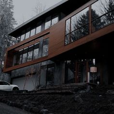 a car is parked in front of a modern house with wood siding and glass windows