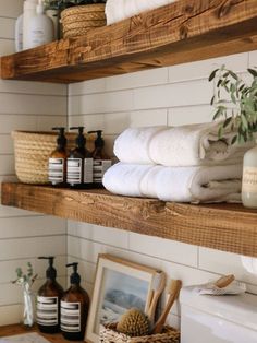 bathroom shelves with towels, soaps and other personal care items on them in a white tiled room