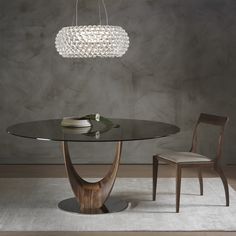 a round glass table with two chairs and a chandelier hanging from the ceiling