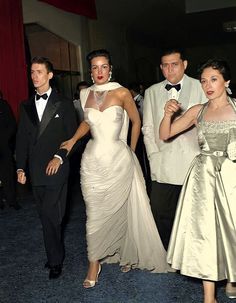 three people in formal wear standing next to each other and one man wearing a tuxedo