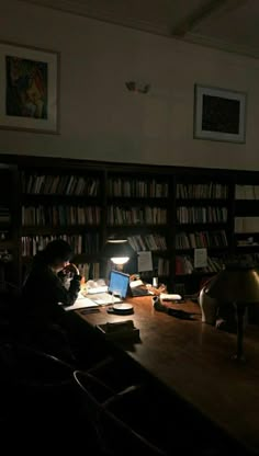 a person sitting at a desk in front of a book shelf with books on it