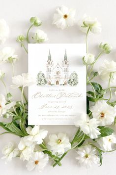 the wedding card is surrounded by white flowers