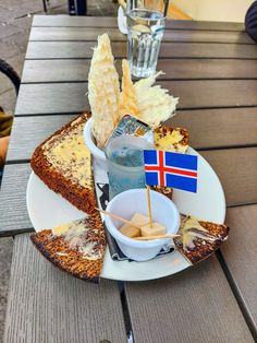 a plate with bread, cheese and other food on it sitting on a wooden table