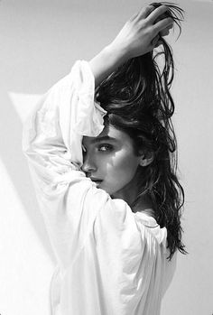 a black and white photo of a woman with her hair blowing in the wind