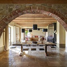 an archway leads to the living room and dining area in this modern home with stone walls