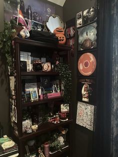 a book shelf filled with lots of books next to a wall covered in pictures and plants