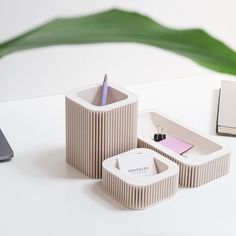 a desk with a laptop, pen and paper holder on it next to a plant