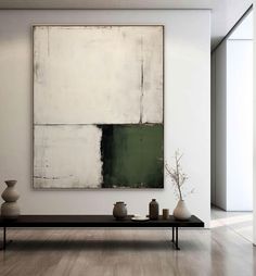 an abstract painting hangs on the wall above a coffee table with vases in front of it