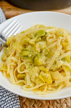 a white plate topped with pasta and broccoli on top of a woven place mat