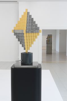 a sculpture made out of legos on display in an empty room with white walls