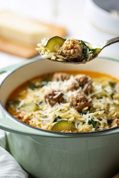 a spoon full of soup with meat and vegetables in it, ready to be eaten