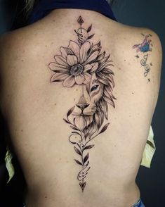 a woman's back with a lion and flower tattoo on it