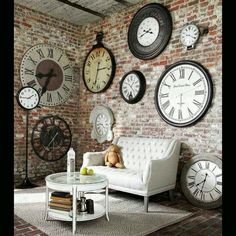 a living room filled with lots of clocks mounted to the wall above a white couch