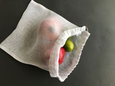 two apples in a white bag on a black surface with one green apple and the other red