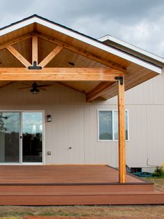 a wooden covered patio with sliding glass doors and wood steps leading up to the front door