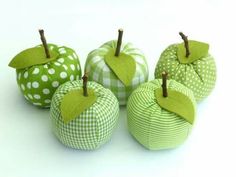 four green apples with white polka dots and one has a leaf on the top, two have leaves on the bottom