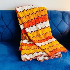 an orange and yellow blanket sitting on top of a blue couch