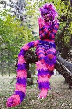 a woman in purple and pink costume sitting on a tree branch with mushrooms around her