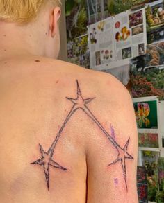 the back of a man's shoulder with three star tattoos on his left side