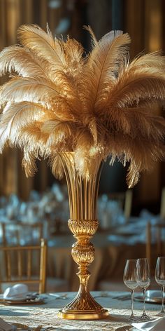 a tall vase filled with lots of feathers on top of a table next to wine glasses