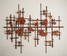 a wall sculpture made out of rusty metal rods and wooden crosses with buttons on them