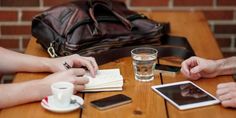 two people are sitting at a table with their tablet