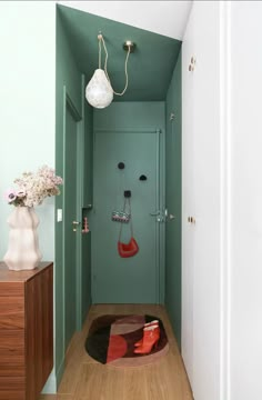 a bathroom with green walls and wooden floors, including a door leading to the toilet