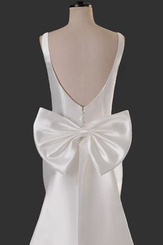 the back of a white dress with a large bow on it's neckline