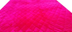 a bright pink quilted blanket on top of a bed