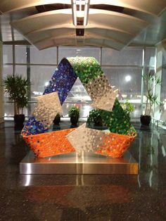 a sculpture made out of glass and pebbles in front of a large window at an airport