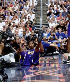 a basketball player sitting on the floor holding up his shoes