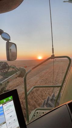 the sun is setting over an open field as seen from inside a vehicle on a farm