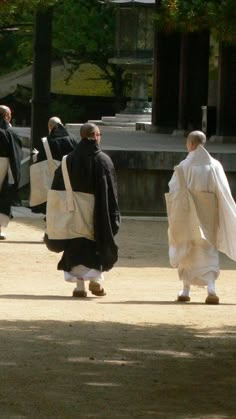 several men dressed in black and white walking down the street with bags on their backs