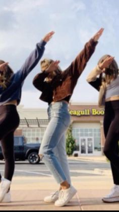 four young women are dancing in front of a store