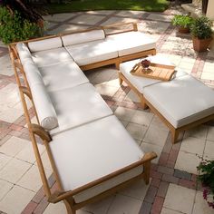 an outdoor patio with white furniture and potted plants on the brick flooring area